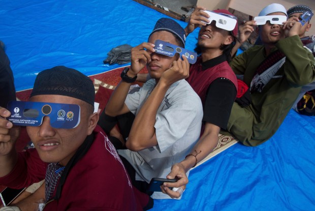 Muslim men watch solar eclipse through safety glasses after a special 'Kusoof' prayer at the campus of the Faculty of Astronomy of Muhammadiah University of North Sumatra (UMSU) in Medan, Indonesia, Thursday, Dec. 26, 2019. People along a swath of southern Asia gazed at the sky in marvel on Thursday at a "ring of fire" solar eclipse. (AP Photo/Binsar Bakkara)