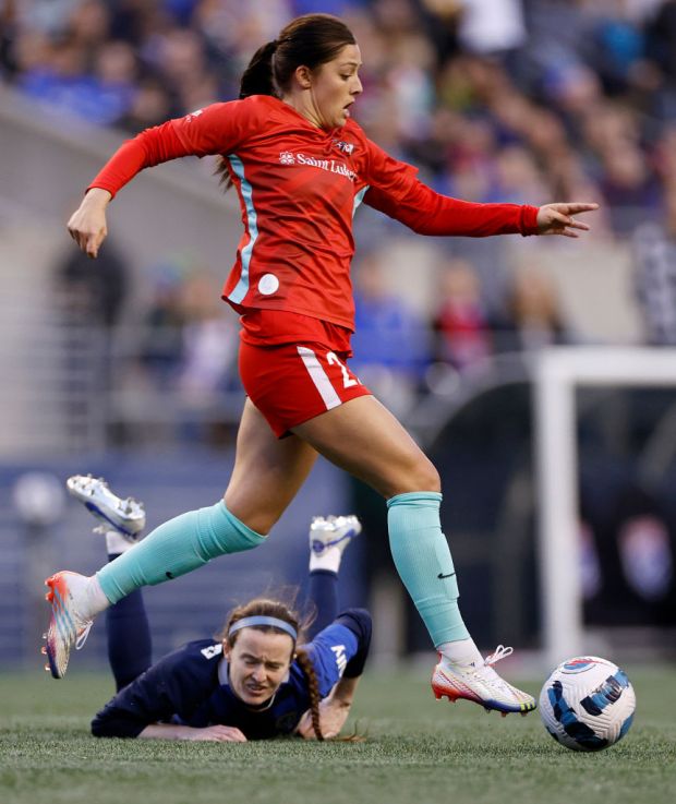 SEATTLE, WASHINGTON - OCTOBER 23: Rose Lavelle #16 of OL Reign falls as Alex Loera #22 of Kansas City controls the ballduring the second half in a NWSL semifinal match at Lumen Field on October 23, 2022 in Seattle, Washington. (Photo by Steph Chambers/Getty Images)