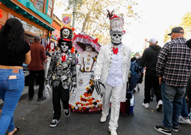 From left to right Angel Gonzalez, 13, from San Jose, with his parents Andrea and Alfredo, walk down International Boulevard during the Dia de los Muertos Festival in Oakland, Calif., on Sunday, Oct. 30, 2022. (Nhat V. Meyer/Bay Area News Group)