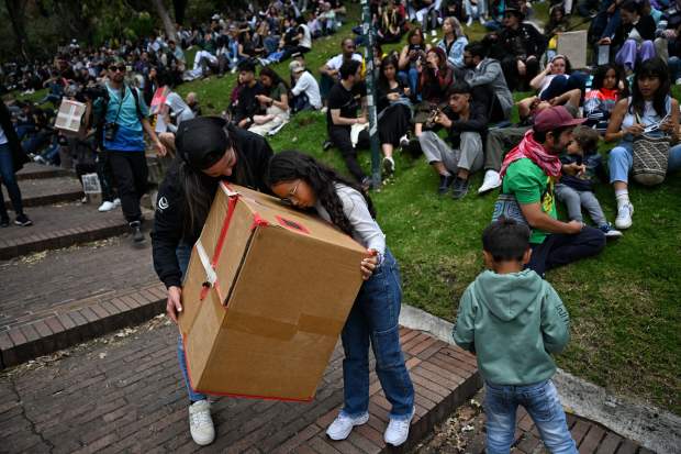 People use a box pinhole projector to watch the annular solar eclipse in Bogota on October 14, 2023. Skygazers across the Americas turned their faces upwards Saturday for a rare celestial event: an annular solar eclipse. (Photo by JUAN BARRETO/AFP via Getty Images)