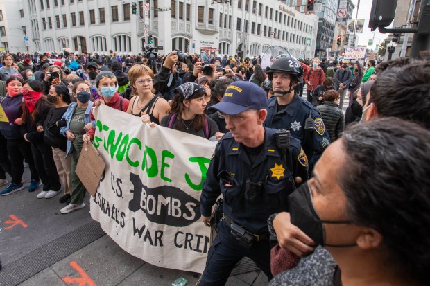 San Francisco police officers pass through a group of protesters blocking access to the Asia-Pacific Economic Cooperation summit in San Francisco, Calif., Wednesday, Nov. 15, 2023. (Karl Mondon/Bay Area News Group)