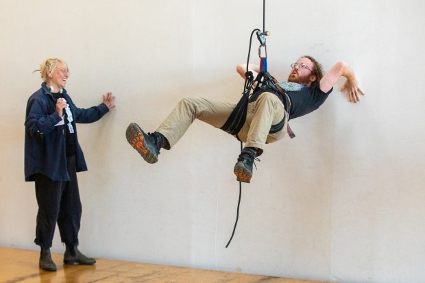OAKLAND, CA - NOVEMBER 12: Tim Hausler of Oakland (right) performa an arial maneuver while attached to a rope connected to a harness while instructor Krystal Harfert (left) looks on during a flight test vertical dance lesson at the BANDALOOP open house at their studio space in Oakland, Calif. on Nov. 12, 2023. BANDALOOP is a renown vertical dance troupe, that have performed their aerial mid-air performances on international landmarks around the world. (Douglas Zimmerman/Special to the Bay Area News Group)
