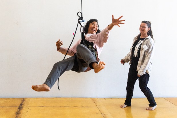 OAKLAND, CA - NOVEMBER 12: May Funabiki of Alameda (left) performs an arial maneuver while hanging from a rope attached to a harness while instructor Sarah Keeney looks on during a flight test vertical dance lesson at the BANDALOOP open house at their studio space in Oakland, Calif. on Nov. 12, 2023. BANDALOOP is a renown vertical dance troupe, that have performed their aerial mid-air performances on international landmarks around the world. (Douglas Zimmerman/Special to the Bay Area News Group)