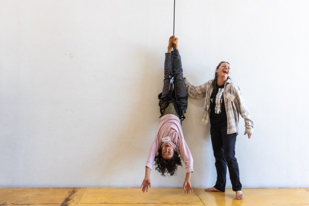 OAKLAND, CA - NOVEMBER 12: May Funabiki of Alameda (left) hangs from a rope attached to a harness while instructor Sarah Keeney looks on during a flight test vertical dance lesson at the BANDALOOP open house at their studio space in Oakland, Calif. on Nov. 12, 2023. BANDALOOP is a renown vertical dance troupe, that have performed their aerial mid-air performances on international landmarks around the world. (Douglas Zimmerman/Special to the Bay Area News Group)