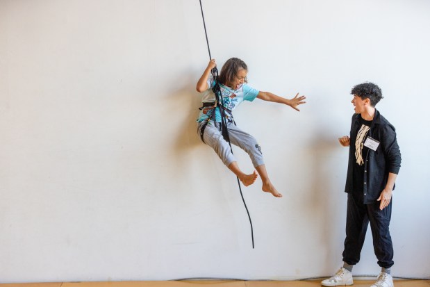 OAKLAND, CA - NOVEMBER 12: Memo Rehberg (left) attempts to hi-five instructor Becca Dean while swinging on a rope attached to a harness during a flight test vertical dance lesson at the BANDALOOP open house at their studio space in Oakland, Calif. on Nov. 12, 2023. BANDALOOP is a renown vertical dance troupe, that have performed their aerial mid-air performances on international landmarks around the world. (Douglas Zimmerman/Special to the Bay Area News Group)