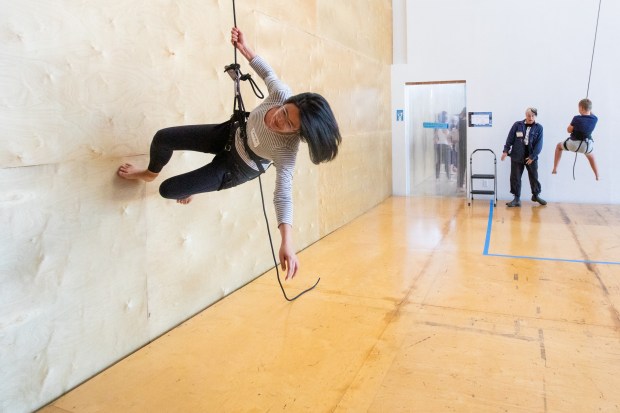 OAKLAND, CA - NOVEMBER 12: Carolyn Choy of Berkeley runs along a wall while hanging from a rope attached to a harness during a flight test vertical dance lesson at the BANDALOOP open house at their studio space in Oakland, Calif. on Nov. 12, 2023. BANDALOOP is a renown vertical dance troupe, that have performed their aerial mid-air performances on international landmarks around the world. (Douglas Zimmerman/Special to the Bay Area News Group)