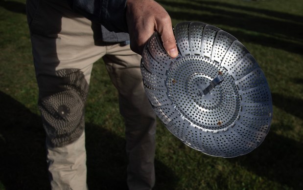 Gray Chang of Palo Alto uses a colander as a pinhole camera to view the crescent suns projected on his pants during an eclipse viewing event at Stanford University, Saturday, Oct. 14, 2023, at (Karl Mondon/Bay Area News Group)