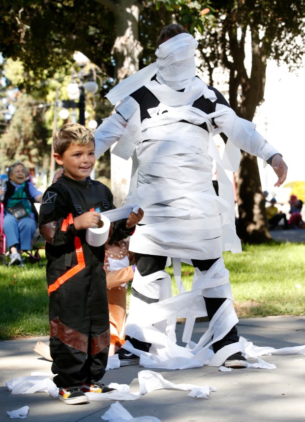 J.D. Manak beams with pride after turning his father, Jonny Manak into a mummy during a Halloween celebration at History Park, Sunday, Oct. 28, 2018, in San Jose, Calif. (Karl Mondon/Bay Area News Group)