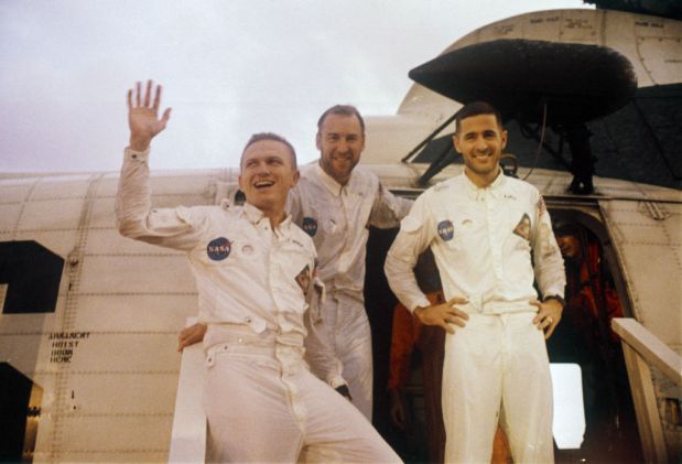 From L to R, Apollo 8 astronauts spacecraft Commander Frank Borman, Command Module Pilot James Lovell and Lunar Module Pilot William Anders, who became the first humans to escape Earth's gravity and the first humans to see the far side of the Moon, look up at cheering crewmen on the upper deck of the USS Yorktown, recovery ship for the Apollo 8 mission, 27 December 1968, after having steped from the helicopter which brought them from their landing point in the Pacific ocean. After launching 21 December 1968, the crew took three days to travel to the Moon, orbited it ten times, 20 hours in total, and landed 27 December 1968 in the Pacific. (Photo by - / NASA / AFP) (Photo by -/NASA/AFP via Getty Images)